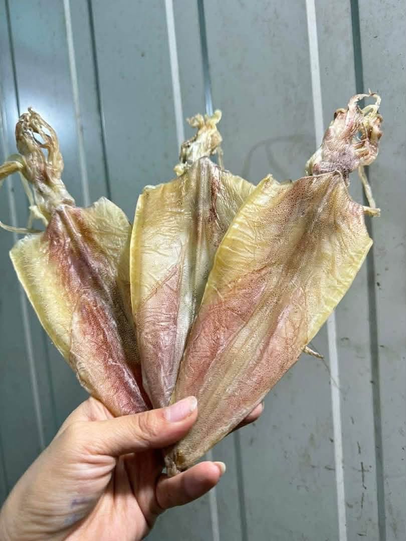 Ba con mực khô cầm trên tay