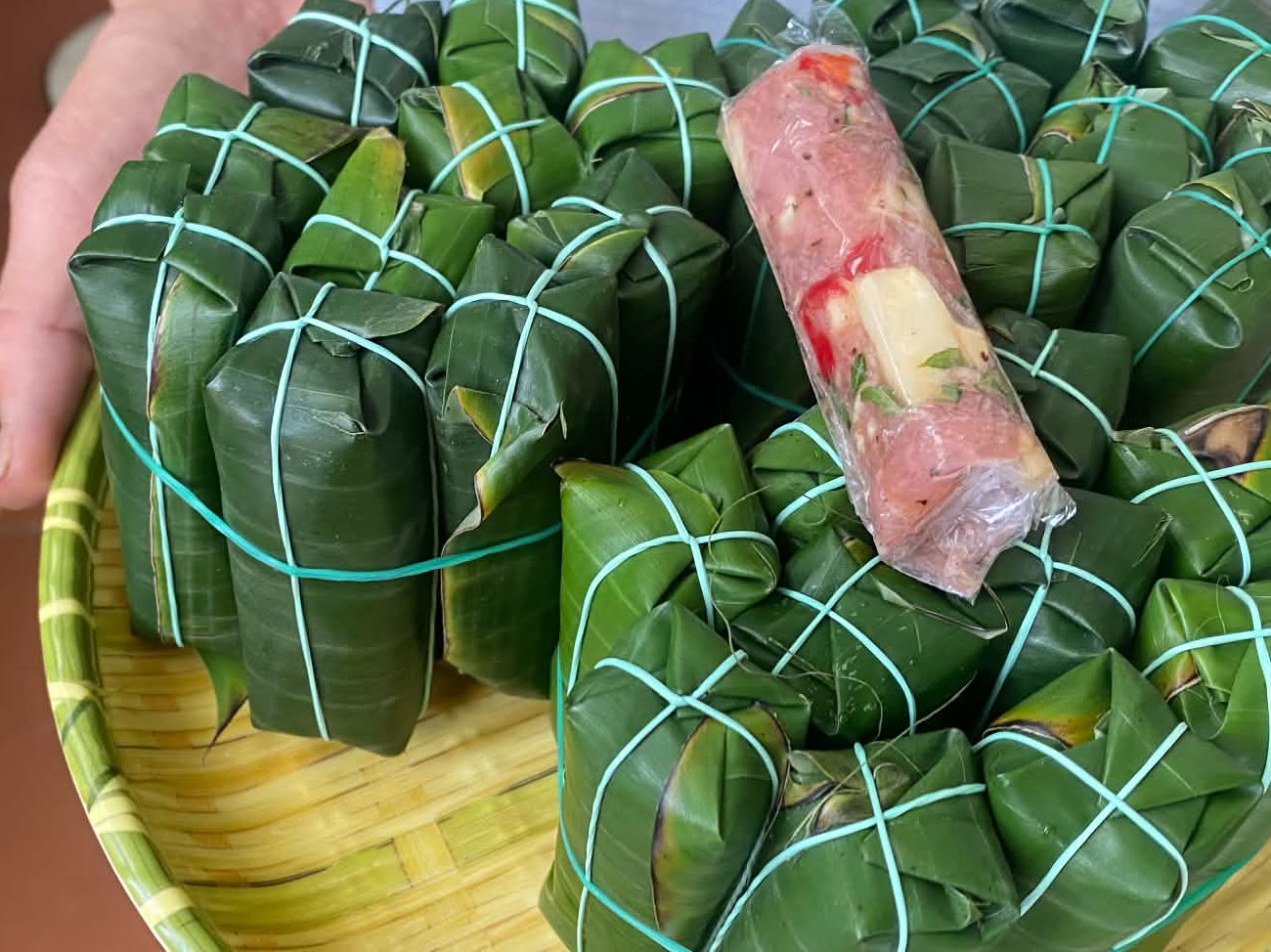 Cận cảnh chiếc nem chua đã bóc lá, thấy thịt hồng, bì và ớt, đặt trên các cọc nem